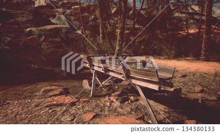 A rustic wooden boat sits peacefully by the edge of some calm waters. Palm trees sway gently in the warm breeze while rocks line the tranquil shore, creating a serene atmosphere. A rustic wooden boat sits peacefully by the edge of some calm waters. Palm trees sway gently in the warm breeze while rocks line the tranquil shore, creating a serene atmosphere. 134380133