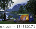 Camping tent on green grass in the morning, antique gas lamps, retro chairs, with outdoor coffee-making facilities on tables in a forest camping area. 134380171