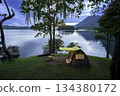 Camping tent on green grass in the morning, antique gas lamps, retro chairs, with outdoor coffee-making facilities on tables in a forest camping area. 134380172