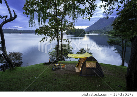 Camping tent on green grass in the morning, antique gas lamps, retro chairs, with outdoor coffee-making facilities on tables in a forest camping area. 134380172