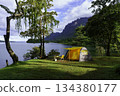 Camping tent on green grass in the morning, antique gas lamps, retro chairs, with outdoor coffee-making facilities on tables in a forest camping area. 134380177