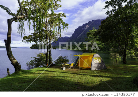 Camping tent on green grass in the morning, antique gas lamps, retro chairs, with outdoor coffee-making facilities on tables in a forest camping area. 134380177