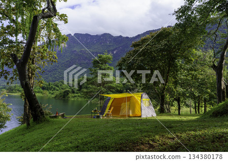 Camping tent on green grass in the morning, antique gas lamps, retro chairs, with outdoor coffee-making facilities on tables in a forest camping area. 134380178