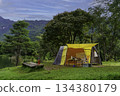 Camping tent on green grass in the morning, antique gas lamps, retro chairs, with outdoor coffee-making facilities on tables in a forest camping area. 134380179