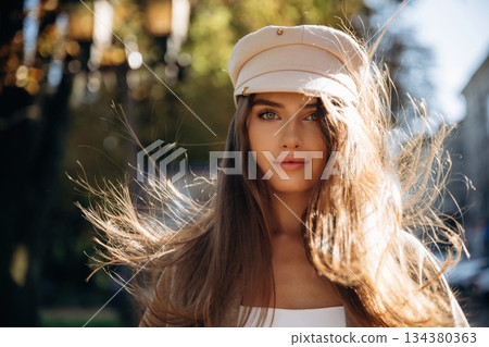 In white hat. Beautiful woman is outdoors in the town In white hat. Beautiful woman is outdoors in the town 134380363