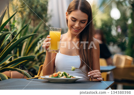 Outdoors of the restaurant. Beautiful young woman is sitting by the table Outdoors of the restaurant. Beautiful young woman is sitting by the table 134380398