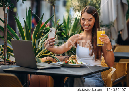 Modern smartphone, by the the table. Beautiful young woman is outdoors of the restaurant Modern smartphone, by the the table. Beautiful young woman is outdoors of the restaurant 134380407