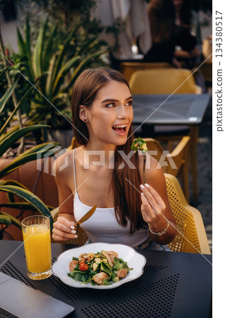 Tasting delicious food. Beautiful young woman is outdoors of the restaurant by the table Tasting delicious food. Beautiful young woman is outdoors of the restaurant by the table 134380517