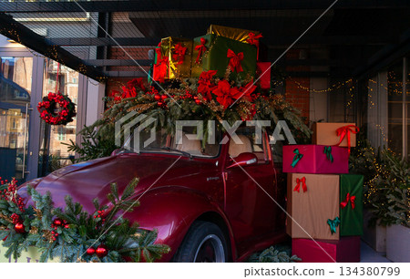 Classic car decorated for Christmas with gifts and greenery in a festive setting Classic car decorated for Christmas with gifts and greenery in a festive setting 134380799