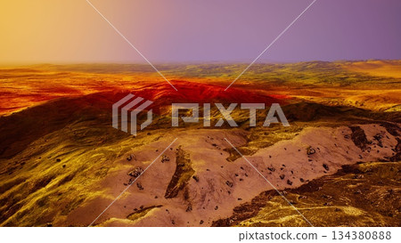 Golden light bathes the expansive desert landscape as the sun sets in the horizon. Rugged hills contrast with the vibrant colors, creating a serene and dramatic scene in nature. 134380888