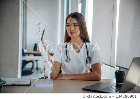 Spine model on the table. Professional female doctor in the clinic indoors 134380901