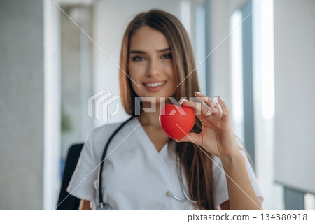 Little red heart in hands. Professional female doctor in the clinic indoors Little red heart in hands. Professional female doctor in the clinic indoors 134380918