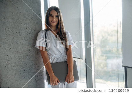 Laptop is in hands. Professional female doctor in the clinic indoors 134380939