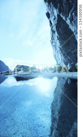 A beautiful mountain lake mirrors the stunning cliffs surrounding it. The sun shines brightly, illuminating the clear water and creating a peaceful atmosphere in nature. A beautiful mountain lake mirrors the stunning cliffs surrounding it. The sun shines brightly, illuminating the clear water and creating a peaceful atmosphere in nature. 134380956