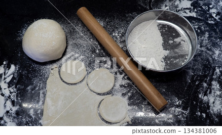 Making Dumplings Dough with Rolling Pin and Flour on Dark Background 134381006