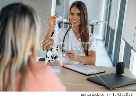 Spine problems, showing issue on model. Woman is on the consultation with doctor in clinic 134381038