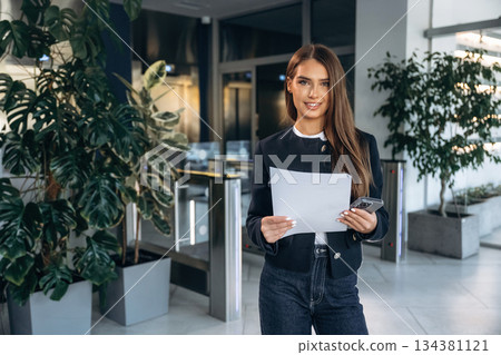 Front view, holding document. Woman is indoors, professional manager of the place 134381121