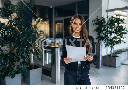 Front view, holding document. Woman is indoors, professional manager of the place Front view, holding document. Woman is indoors, professional manager of the place 134381122