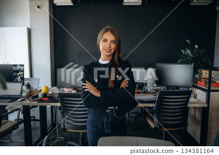 With arms crossed, standing. Cheerful beautiful woman is standing indoors 134381164