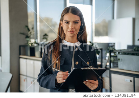 Black notepad and a pen in hands. Woman is working in the office Black notepad and a pen in hands. Woman is working in the office 134381194