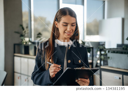 Black notepad and a pen in hands. Woman is working in the office Black notepad and a pen in hands. Woman is working in the office 134381195