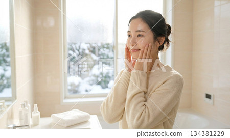 一位二十多歲的日本女性塗抹潤膚露後感覺略微滋潤 | 冬日清晨，略帶拉扯感的護膚品廣告風格 134381229