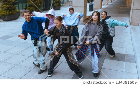Group of dancers moving in sync in open city space. Group of dancers moving in sync in open city space. 134381609
