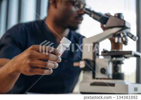 Doing research. Scientist is working indoors, microscope is on the table Doing research. Scientist is working indoors, microscope is on the table 134381892