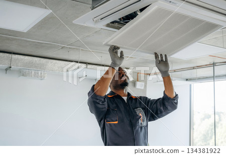 Fixing the ventilation. Repairman is indoors in the modern office 134381922