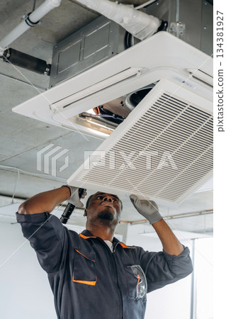 Broken ventilation, fixing it. Repairman is indoors in the modern office 134381927