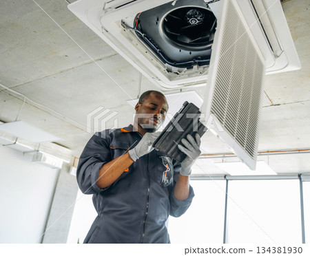 Broken ventilation, fixing it. Repairman is indoors in the modern office 134381930