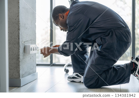 Process of installation of the socket. Repairman is indoors in the modern office 134381942