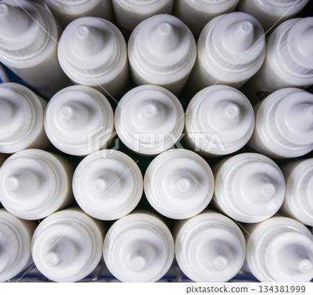 Close-up texture of grouped white plastic dropper containers for pharmaceuticals, cosmetics, or laboratory use. Top view 134381999