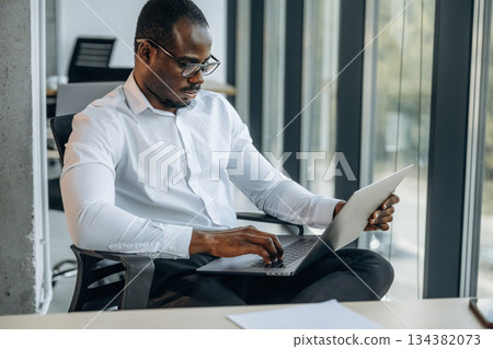 With laptop. Businessman is working in modern office With laptop. Businessman is working in modern office 134382073