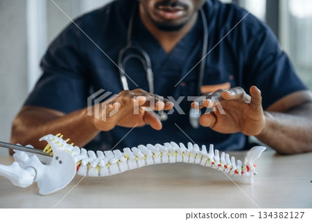 Educational stuff. Model of human spine. Professional doctor is in his office indoors Educational stuff. Model of human spine. Professional doctor is in his office indoors 134382127