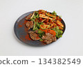 Salad with grilled veal and vegetables on a dark plate on a white background, restaurant serving 134382549