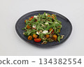Grilled pumpkin salad with arugula and pumpkin seeds with oil on dark plate on a white background 134382554