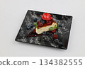 Tasty cheesecake with berries and sauce on a black plate on a white background 134382555