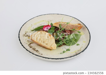 Veal tartare with dry wheat bread on a white plate on a white background Veal tartare with dry wheat bread on a white plate on a white background 134382556