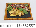 Tasty beef tongue pieces, basil and potatoes on dark wooden dish on white background 134382557