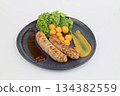 Grilled sausages with green lettuce and potato croquettes on a dark plate on white background 134382559
