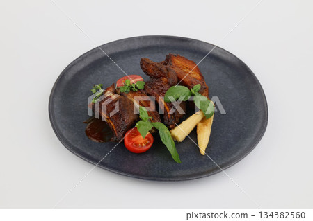 Grilled spare ribs on plate over black stone background on a white background Grilled spare ribs on plate over black stone background on a white background 134382560