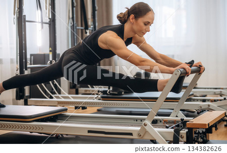 Side view, doing exercises. Young woman is in the gym with training equipment 134382626