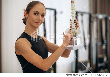 Take a look at spine model. Young woman is in the gym with training equipment Take a look at spine model. Young woman is in the gym with training equipment 134382637