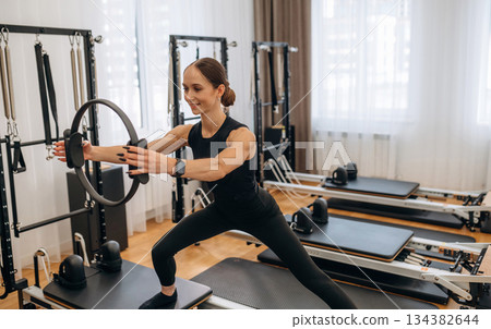 Standing, doing fitness. Young woman is in the gym with training equipment Standing, doing fitness. Young woman is in the gym with training equipment 134382644
