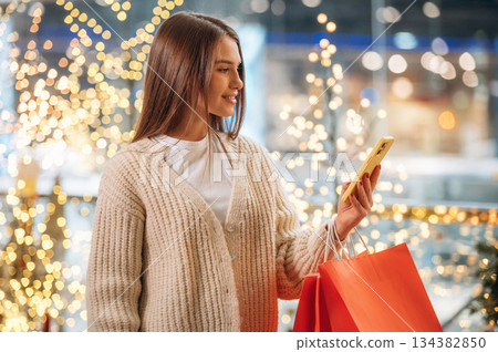Red shopping bags. New year presents. Woman is near the Christmas tree Red shopping bags. New year presents. Woman is near the Christmas tree 134382850