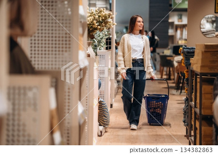 Blue basket is on the floor. Woman is in the shop with decoration, indoors Blue basket is on the floor. Woman is in the shop with decoration, indoors 134382863