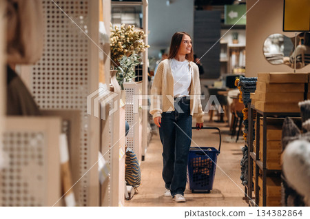 Blue basket is on the floor. Woman is in the shop with decoration, indoors Blue basket is on the floor. Woman is in the shop with decoration, indoors 134382864