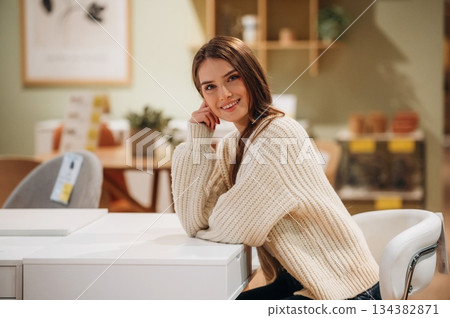 Beautiful smiling woman is sitting by the table on the kitchen 134382871