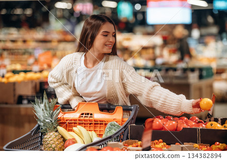 With tomatoes. Beautiful woman is in the supermarket 134382894